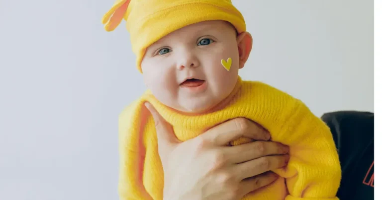 Baby in a yellow outfit with a heart sticker on cheek names starting with v