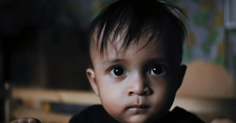 Baby with wide eyes staring directly into the camera in low light – names that mean death.