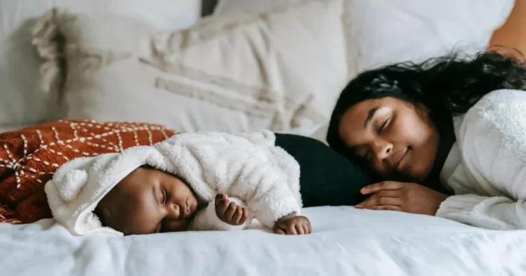 Infant sleeping on side in cozy white hoodie with mother resting beside on bed ,infant sleeping on side
