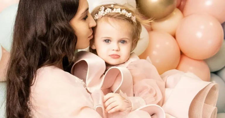 A mother holding her young daughter dressed in a pink gown with a large bow, surrounded by pastel balloons – irish girl names