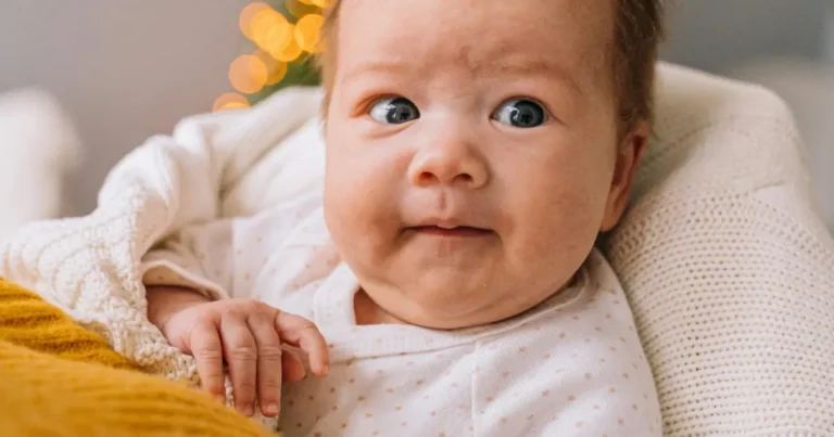 Baby with curious eyes looking up while wrapped in a white blanket ,biblical girl name