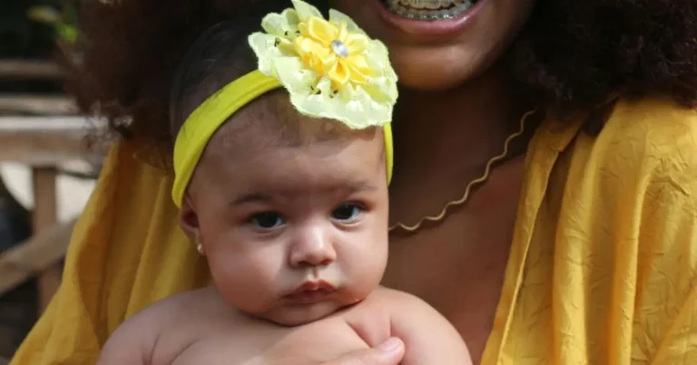 Adorable baby girl in yellow flower headband being held, representing natural beauty and cultural pride in African American names for girls