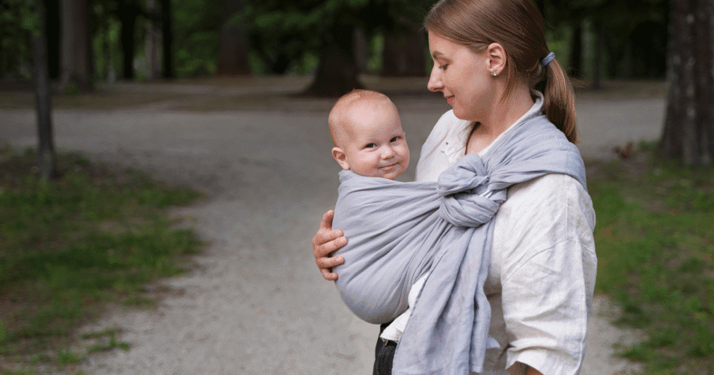 A woman holds her baby outdoors, with Woven wrap for newborn