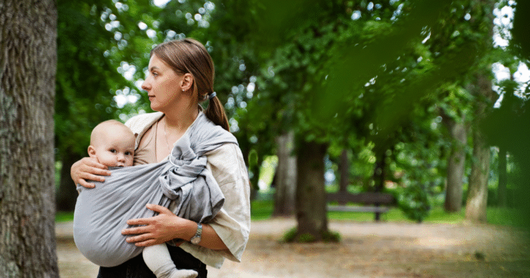 A woman holds her baby outdoors, with Woven wrap for newborn