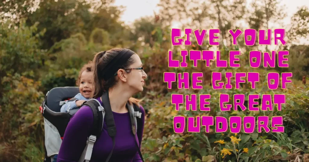 Mother hiking through a wooded trail with a toddler in a hiking backpack carrier. Text overlay reads: “Give your little one the gift of the great outdoors.”