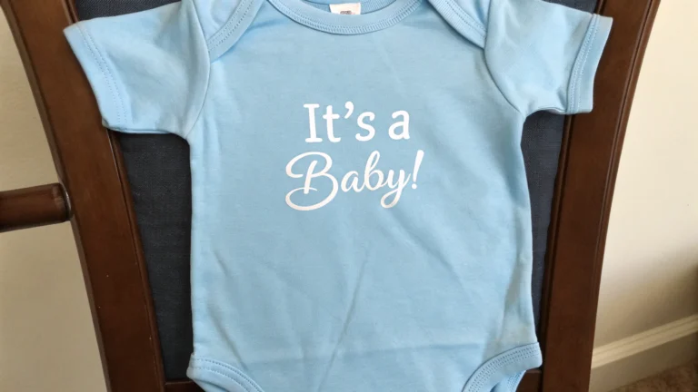 Blue pregnancy announcement onesie with the text It’s a Baby! displayed on a chair.