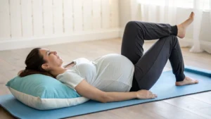 Pregnant woman lying on a yoga mat doing gentle pregnancy sciatica stretches with pillow support.