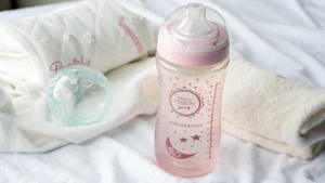 Pink pregnancy water bottle with measurement markings placed on soft fabric, ideal for expecting moms.