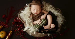 A newborn baby sleeping in a basket surrounded by berries and traditional Vietnamese decor